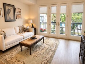 A living room with a sofa, coffee table, and artwork on the wall. - The Jardin Briar Suite | Near Downtown (Savannah)
