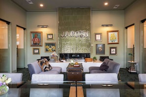 Un hall d’hôtel moderne avec deux canapés, une table basse, des œuvres d’art encadrées et un grand panneau métallique.