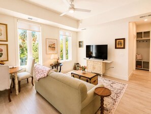 Ein Wohnzimmer mit einer Couch, einem Couchtisch, einem Fernseher und einem Essbereich mit Tisch und Stühlen.