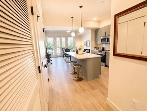 A modern kitchen with a central island, stainless steel appliances, and pendant lighting. - The Jardin Elm Suite | Near Downtown (Savannah)