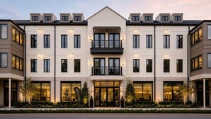 Ein mehrstöckiges Hotel mit zentralem Eingang, Balkonen und einer gut beleuchteten Fassade.