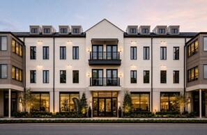 A multi-story hotel with a central entrance, balconies, and a well-lit facade. - The Jardin Elm Suite | Near Downtown (Savannah)