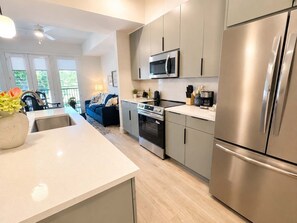 Een moderne keuken met roestvrijstalen apparatuur, een centraal eiland en uitzicht op een balkon.