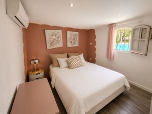 Ein Schlafzimmer mit Bett, Nachttisch, Lampe und Kunstwerk an der Wand.