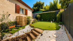 Ein Garten mit Rasen, einer Holzbank, einem kleinen Tisch und einer Steinmauer.