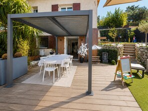 Eine Terrasse im Freien mit überdachter Essgegend, einem Holzdeck und einer Steinmauer.