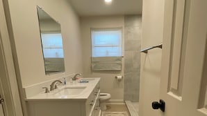 Casa de banho pequena com lavatório duplo, sanita e zona de duche.