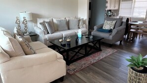 Uma sala de estar com sofá, mesa de centro e um espaço de jantar com mesa e cadeiras.