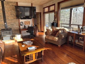 Ein gemütliches Blockhauss mit Kamin, Fernseher, Sofa und Holztisch.