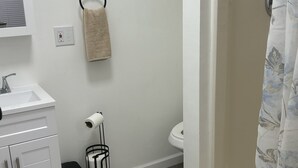 Ein Badezimmer mit weißem Waschbecken, WC und Duschvorhang.