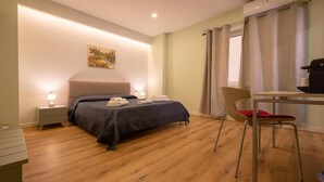 Een hotelkamer met een bed, nachtkastje, stoel en bureau met een computer.