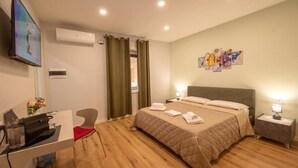 Hotelkamer met een bed, bureau, stoel, televisie en kunst aan de muur.