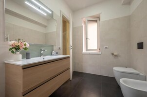 Un bagno moderno con uno specchio grande, un mobile lavabo, un water e una doccia.