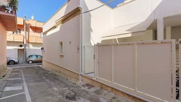 A narrow street with a parked car and a building with a gated entrance.