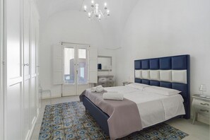 A hotel room with a bed, a nightstand, a mirror, a chandelier, and a patterned rug. - Dimora Collina 2 holiday home near Gallipoli and Salento beaches (Sannicola)