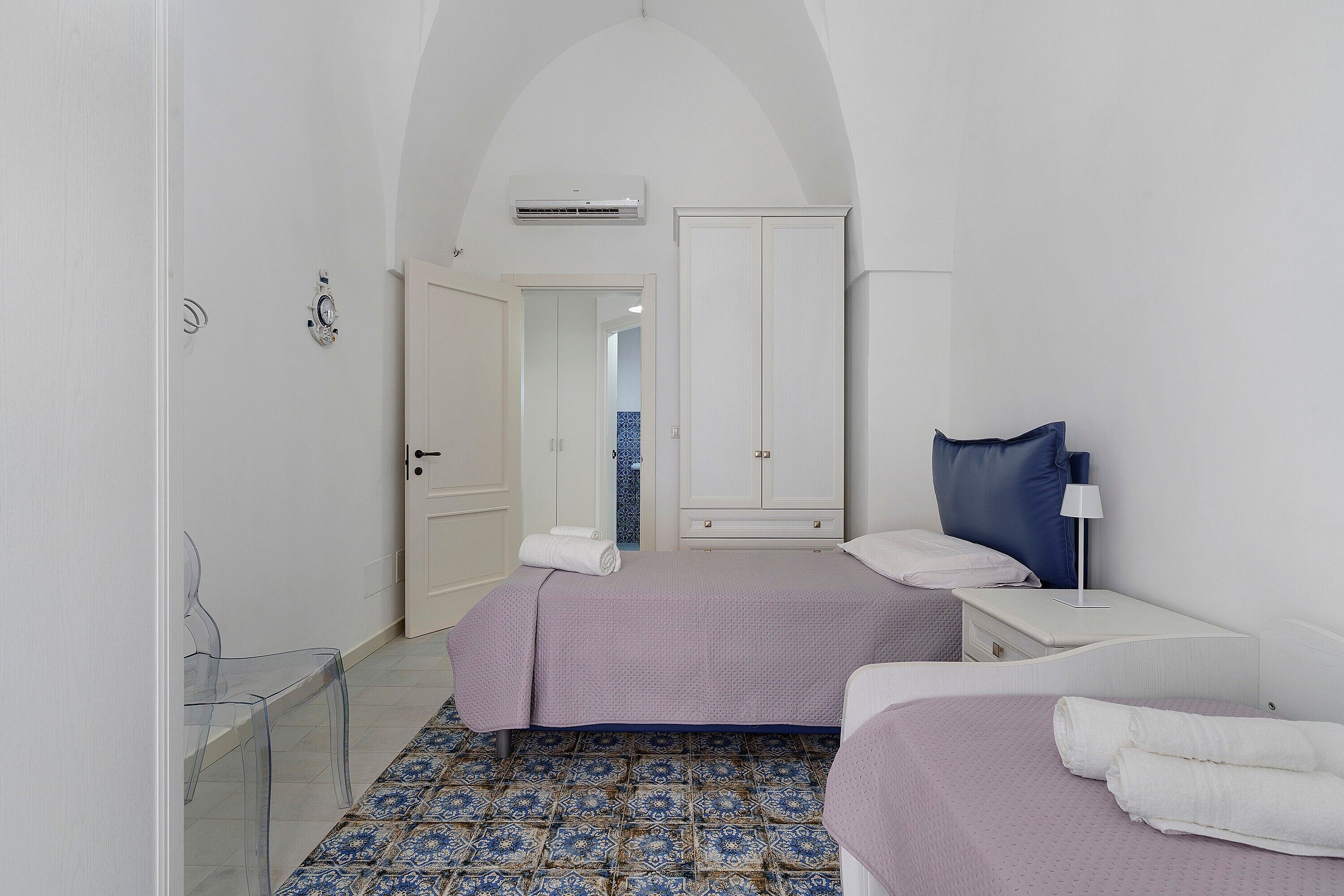 A hotel room with a bed, bedside tables, a chair, a desk, and a wardrobe.
