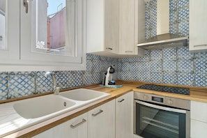 Una cocina con un lavamanos blanco, una cafetera y un horno moderno.