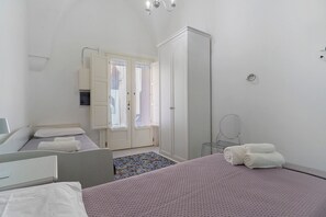 Habitación con dos camas, un armario, un espejo y un baño visible a través de una puerta.