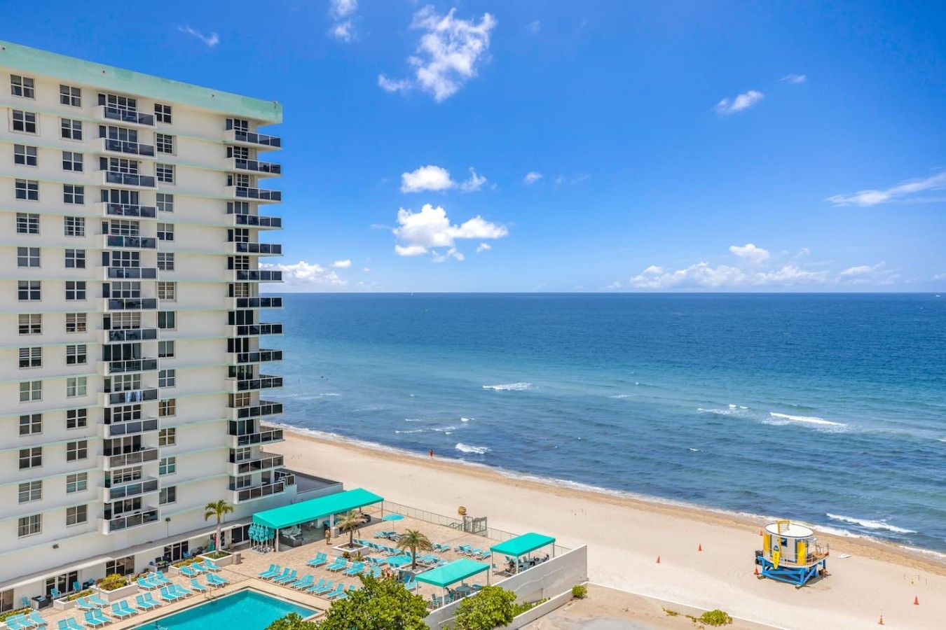 Un hotel de gran altura con piscina, playa y vista al océano.