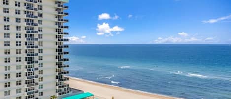 A high-rise hotel with a pool, beach, and ocean view.