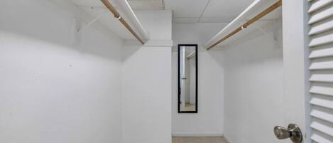 Un pasillo estrecho con paredes blancas, piso de baldosas y una puerta con manija de metal.