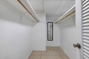A narrow hallway with white walls, a tiled floor, and a door with a metal handle. - Vive la experciencia frente al mar (Hollywood)
