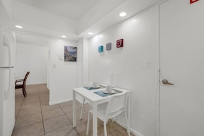 A small dining area with a table and chairs, a painting on the wall, and a door with a wine and dine sign. - Vive la experciencia frente al mar (Hollywood)