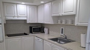 A kitchen with white cabinets, a microwave, a sink, and a dishwasher. - Vive la experciencia frente al mar (Hollywood)