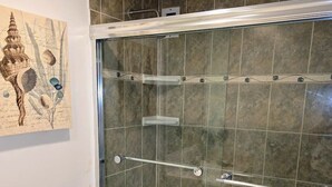A bathroom with a glass-enclosed shower, a toilet, and a sink. - Vive la experciencia frente al mar (Hollywood)