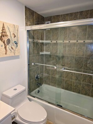 A bathroom with a glass-enclosed shower, a toilet, and a sink. - Vive la experciencia frente al mar (Hollywood)