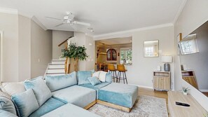 Ein modernes Wohnzimmer mit einer Eckcouch, einem Essbereich und einer Treppe.
