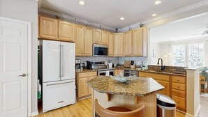 Una cocina moderna con armarios de madera, encimeras de granito y electrodomésticos de acero inoxidable.