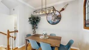 En matplats med ett träbord, blå stolar, en hängande lampa och en tavla som hänger på väggen.