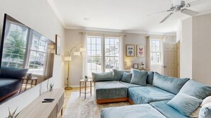 A modern living room with a sectional sofa, a flat-screen TV, and a ceiling fan. - Rehoboth Crossing - 37063 Turnstone Cir (Rehoboth Beach)