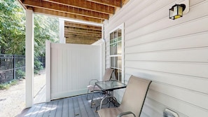 A covered porch with a table and chairs, a wooden ceiling, and a white exterior wall. - Rehoboth Crossing - 37063 Turnstone Cir (Rehoboth Beach)