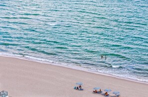 A beach with people in the water and beach chairs under umbrellas. - Hollywood Escape |Piscina| Playa | Vistas | Balcón (Hollywood)