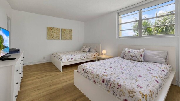 Un dormitorio con dos camas, televisión y obras de arte en la pared.