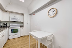 A compact kitchen with white cabinetry, a microwave, an oven, a coffee maker, and a wall clock. - Hollywood Escape |Piscina| Playa | Vistas | Balcón (Hollywood)