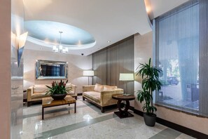 A modern lobby with two sofas, a coffee table, a potted plant, and a large window with a view. - Hollywood Escape |Piscina| Playa | Vistas | Balcón (Hollywood)
