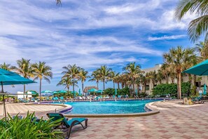 A resort pool area with lounge chairs, umbrellas, and palm trees. - Hollywood Escape |Piscina| Playa | Vistas | Balcón (Hollywood)