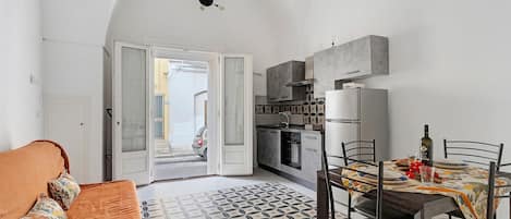 A compact living space with a kitchenette, a dining area with a patterned tablecloth, and a sofa with patterned cushions.