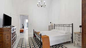 Een slaapkamer met een bed, nachtkastjes, een televisie en een kroonluchter.