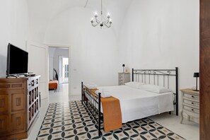 Una camera da letto con un letto, comodini, una televisione e un lampadario.