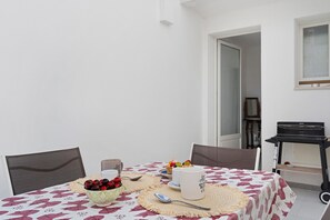 A dining table with a floral tablecloth, a bowl of fruit, and a mug. - Dimora Collina 3 Apartment with Terrace, Wi-Fi, and Air Conditioning (Sannicola)