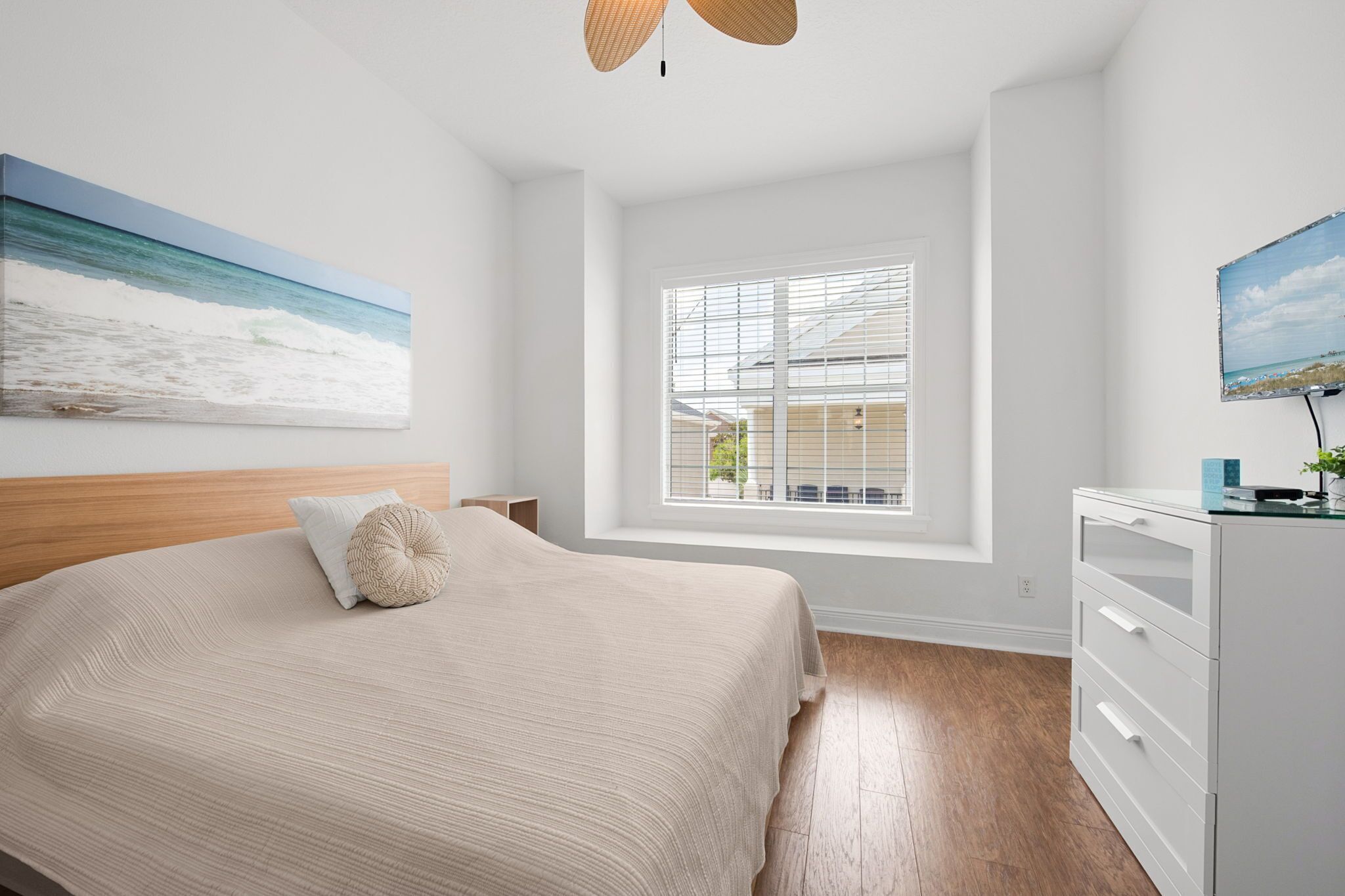 A bedroom with a bed, a window with blinds, a dresser, and a painting on the wall.
