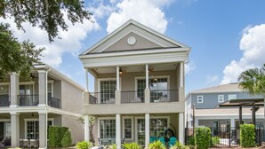 A two-story building with a balcony, large windows, and a covered outdoor area. - Game Room Arcade Games Private Pool Guest House-7521 (Kissimmee)