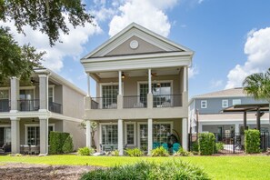 A two-story building with a balcony, large windows, and a covered outdoor area. - Game Room Arcade Games Private Pool Guest House-7521 (Kissimmee)