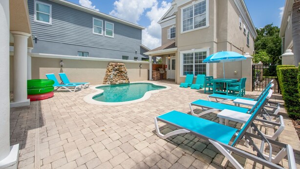 A backyard with a swimming pool, lounge chairs, and a stone wall. - Game Room Arcade Games Private Pool Guest House-7521 (Kissimmee)