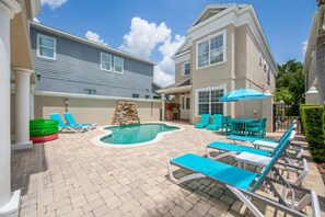 A backyard with a swimming pool, lounge chairs, and a stone wall. - Game Room • Arcade Games • Private Pool • Guest House • 7521 (Kissimmee)