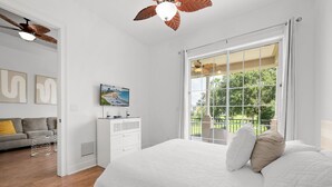 A bedroom with a large bed, a TV, a ceiling fan, and a view of a park through a sliding glass door. - Game Room Arcade Games Private Pool Guest House-7521 (Kissimmee)